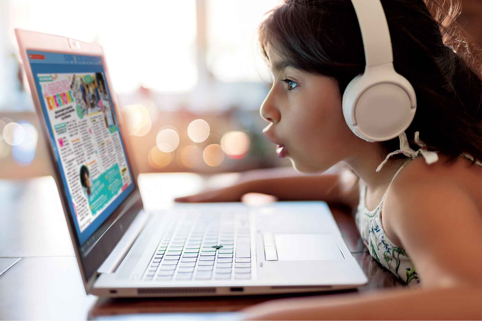 A girl wearing headphones and looking at a laptop